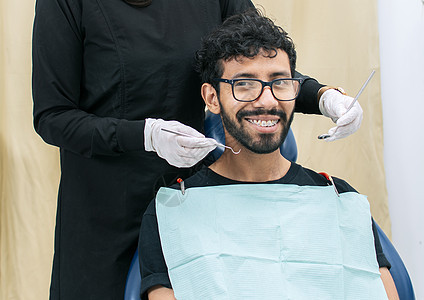 牙医为微笑的病人检查口腔 女牙医为女病人做根管治疗 女牙医和说谎的病人 牙医进行口腔科药品卫生护理口罩设备咨询保健员医学医疗牙科图片