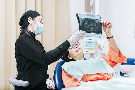 牙医给病人看 X 光片 病人和牙医一起看 X 光片 牙科病人拿着她的 X 光片 牙医用 X 光片检查图片