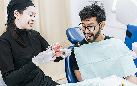 牙医与病人展示假牙 牙医向病人指出假牙 牙医向病人解释牙齿卫生图片