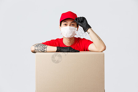 红帽和T恤衫 靠纸板盒或客户包包的快递服务 口贴成订单 将货物转移给维持安全自居住区的人等 都是友善的亚洲人送货员男人购物命令口图片