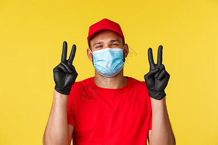 Covid19 送货单 购物 非接触式支付和社交距离概念 可爱的快递员 穿红色制服的男员工 医用面具 展示和平标志 在冠状病毒期图片