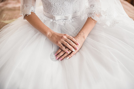 美皮肤新娘的女手 躺在白色婚纱上的白礼服上美甲蕾丝套装婚礼沙龙女士裙子乳罩证人玫瑰图片