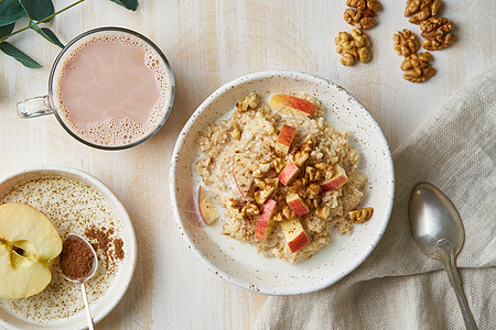 燕麦片配苹果 坚果 蜂蜜和白色木质浅色背景上的巧克力杯 顶视图 健康饮食早餐图片