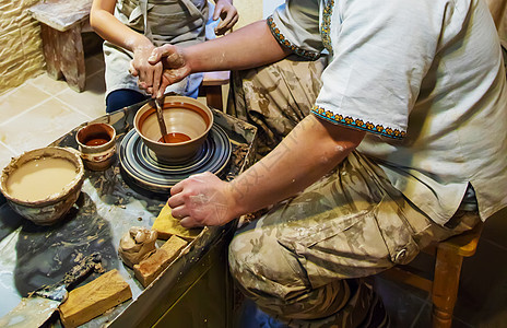主人和学生的手在黄色粘土的波特车轮上做一个投手 有选择地集中注意力于手水壶造型杯子手指黏土陶器作坊手工业陶瓷模具图片