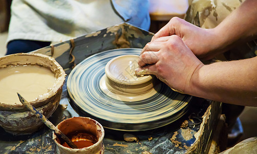 主人和学生的手在黄色粘土的波特车轮上做一个投手 有选择地集中注意力于手杯子男人陶瓷手工文化黏土制品工匠创造力陶器图片