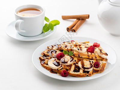比利时华夫饼 包括草莓 香蕉 巧克力糖浆和白本茶早餐图片