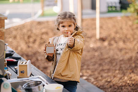 可爱的小女孩在户外的玩具厨房里玩耍 可爱的三岁女孩在儿童城玩得开心喜悦中心厨师市场幼儿园童年食物桌子托儿所盘子图片