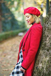 温柔的女士在秋天公园靠在树上图片