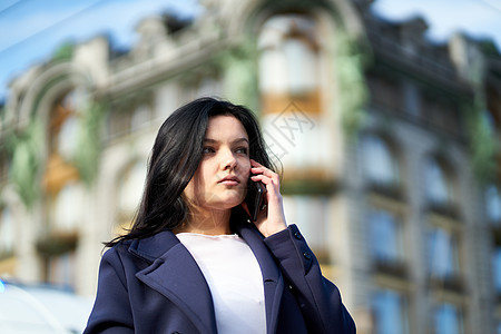 长头发的女人正在打电话 秋天或冬天 户外的女孩 市中心圣彼得堡街道上漂亮聪明的黑发女郎 复制空间电话街道蓝色技术城市外套讲话快乐图片