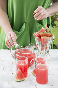 一个穿绿裙子的女人 从西瓜里倒红酒来清净玻璃液体排毒收成饮食果汁稻草食物蓝色饮料图片