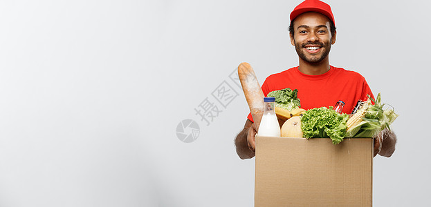 交付概念  英俊的非洲裔美国人送货员携带从商店运来的食品和饮料包箱 孤立在灰色工作室背景上 复制空间顾客幸福杂货店食物蔬菜店铺微图片