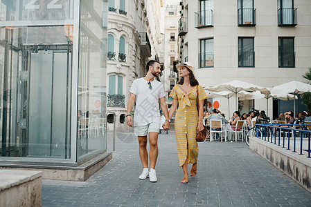 一个戴着帽子的女孩和她有胡子的男朋友 正在穿过老城里走来走去图片