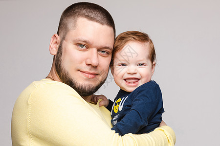 快乐父亲的肖像 带着可爱笑容的孩子微笑工作室拥抱婴儿乐趣父母肩膀儿子成人蓝色图片