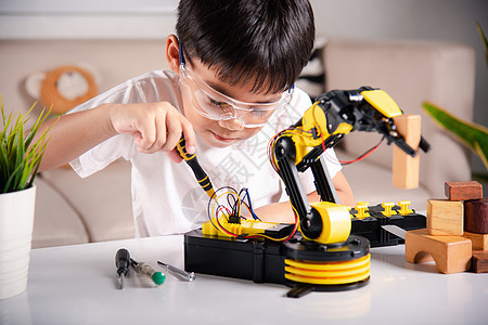 快乐的亚洲小男孩利用螺丝起子 在家庭车间修补机器人机械臂合身乐趣检查金属技术员教育工程师实验室维修男生科学图片