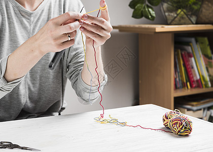 女性用手编织着多彩的丝线图片