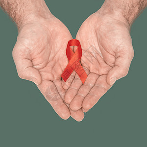 红色意识丝带蝴蝶结勒芒在绿色背景上孤立的帮助之手 艾滋病毒 艾滋病世界日 社会生活问题概念 援助慈善基金的概念 医疗保健和医学概图片