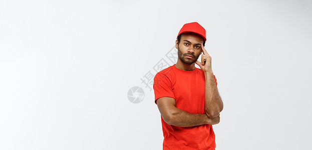 交付概念  英俊的非洲裔美国人送货员认真思考一些事情 在灰色工作室背景上孤立 复制空间衣服手臂思维工作商业盒子红色相机成人职业图片