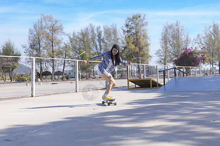 年轻的亚洲女性早上在户外的公园滑板坡道上玩冲浪滑板 快乐的女人在公园玩滑板 体育活动生活方式概念女孩极限青年娱乐闲暇溜冰者运动滚图片