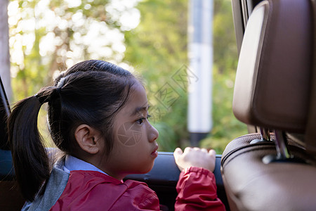 亚洲快乐学生在享受汽车公路旅行时带着相机微笑 早上 女儿微笑着看着车内的相机 亚洲儿童在上学途中坐在车里 车里的一家人图片