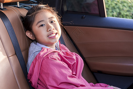 亚洲快乐学生在享受汽车公路旅行时带着相机微笑 早上 女儿微笑着看着车内的相机 在去学校的路上坐在车里的亚洲孩子 车里的一家人车辆图片
