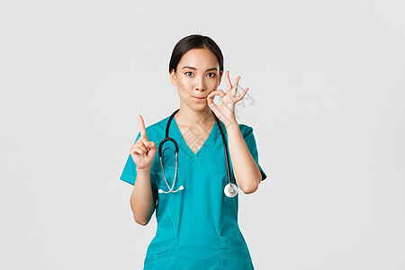 Covid19 保健工作者 大流行病概念 严重看起来忧心忡忡的女护士 医生要求保守秘密 摇动手指和显示口封 拉紧嘴唇手势学校医师图片