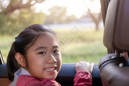 亚洲快乐学生在享受汽车公路旅行时带着相机微笑 早上 女儿微笑着看着车内的相机 在去学校的路上坐在车里的亚洲孩子 车里的一家人思维图片