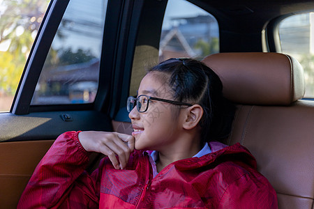 亚洲快乐学生在享受汽车公路旅行时带着相机微笑 早上 女儿微笑着看着车内的相机 在去学校的路上坐在车里的亚洲孩子 车里的一家人表情图片