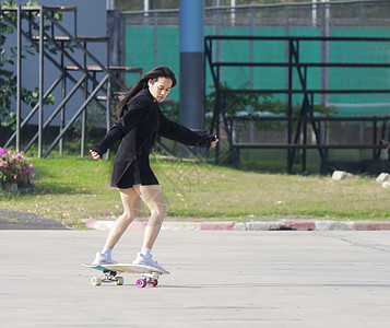 美丽的夏日 亚洲女性在户外玩滑冰板 早上 快乐的年轻女性在公园玩冲浪板 体育活动生活方式概念 年轻女性喜欢使用 SurfSkat图片