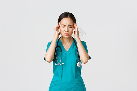Covid19 医护人员 流行病概念 劳累过度 疲惫不堪的年轻亚洲女护士闭上眼睛 因头痛而做鬼脸 头晕 与冠状病毒患者一起夜班 图片