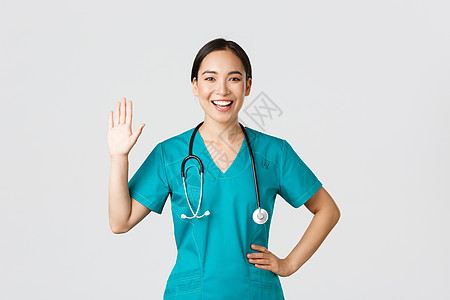 Covid19 医护人员和预防病毒的概念 面带微笑的亚洲女医生 身穿磨砂膏的医生挥手打招呼 你好 问候病人 很高兴见到你专家外科图片