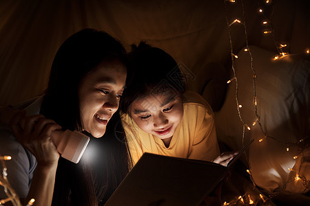 家庭观念 睡前姐姐和姐姐一起用手电筒看书 姐姐在床单帐篷里一起读故事书 重点选择性小姐姐 具有胶片颗粒效果教育喜悦阅读女性幸福妹图片