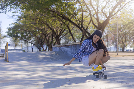 年轻的亚洲女性早上在户外的公园滑板坡道上玩冲浪滑板 快乐的女人在公园玩滑板 体育活动生活方式概念闲暇女士女孩森林溜冰者街道乐趣运图片