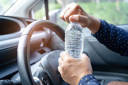 亚洲女司机在开车时拿着瓶子饮水 塑料热水瓶引起火灾 在汽车驾驶期间车辆速度男性成人车轮车速女士奢华安全天空图片