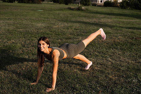 健身女孩在绿色公园做热身和伸展运动 运动生活方式绿色力量运动装运动员运动服太阳健身房女士街道身体图片