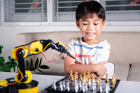 亚洲小男孩在玩机器人机械臂的象棋学校桌子男生教育课堂金属机械技术孩子车库图片