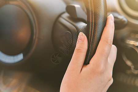 女性在开车时手放在汽车方向盘上图片