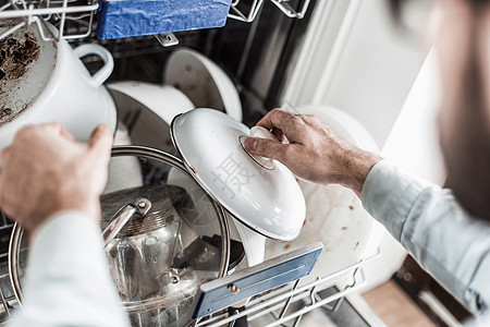 年轻人把洗碗机的盘子拿出来洗碗家政打扫垫圈陶器餐具用具机器男性男人图片
