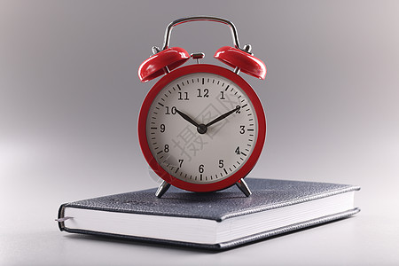 红时钟站在封闭的书本或日记 学习时间 学习新信息的时间之上图片