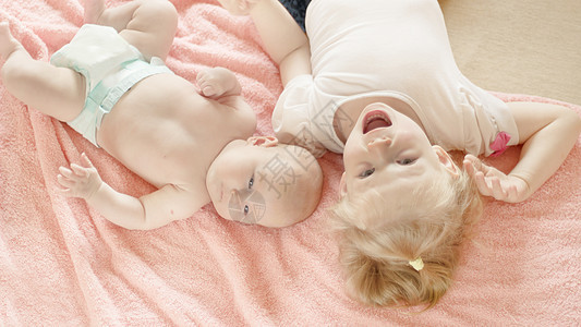 两个小妹妹躺在粉色毯子上图片