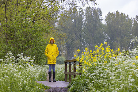 春生带黄雨衣和橡胶靴的年轻女青年季节裙子鞋类乐趣天气女士雨鞋衣服公园女性图片