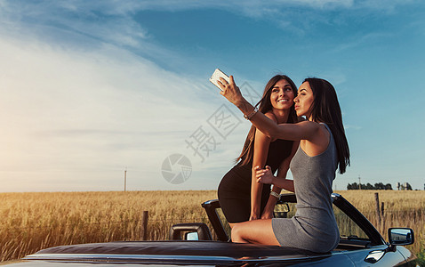 街上拍着两个漂亮女孩的相片微笑自由冒险旅行运输女士驾驶女性朋友女朋友图片