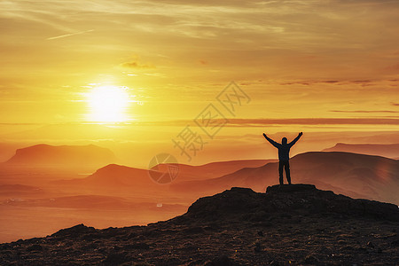 快乐的男人在日落时站在悬崖上海洋游客旅行海滩太阳摄影天空旅游照片风景图片