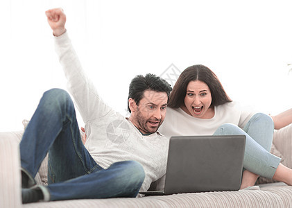 年轻夫妇在他们的笔记本电脑上观看电视节目电视房子男性沙发视频朋友们女性电影娱乐女士图片