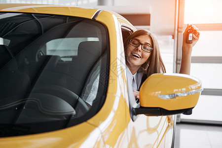 女司机笑着展示新车钥匙执照微笑女性驾驶成人青少年座位旅行驾照车轮图片