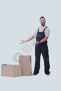 身穿制服的友好男子站在纸板箱旁边 并举足轻重邮递员送货货物导游盒子纸板男性职业工作服务图片