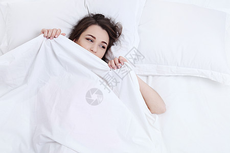 漂亮的女人躺在她家里的床上夫妻寝具说谎女孩睡觉成人眼睛就寝枕头微笑图片
