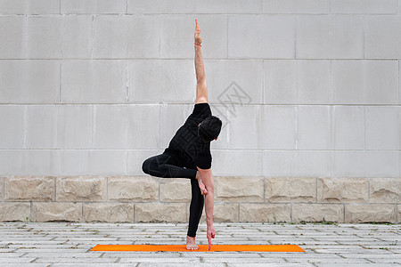 穿黑色运动服的人正在练习平衡和伸展运动 在户外做瑜伽图片