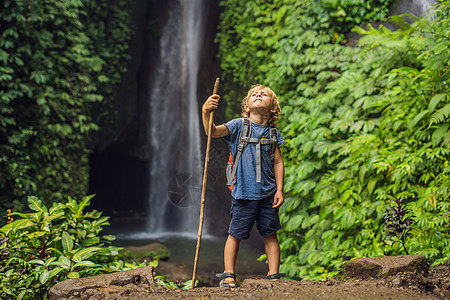 在印度尼西亚巴厘岛Leke Leke的瀑布背景上 男孩子们在路边玩棍子 与儿童一起旅行的概念儿子游客丛林男生池塘苔藓乌布登山杖冒图片