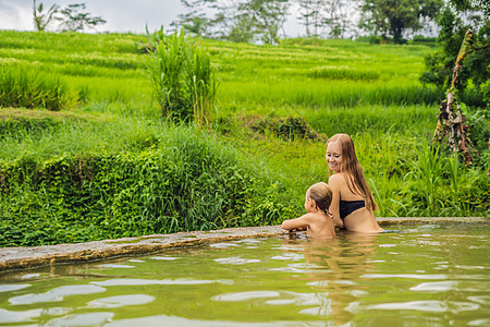 巴厘Belulang温泉的妈妈和儿子旅行者 介绍与儿童一起旅行的水稻梯田概念的背景图片