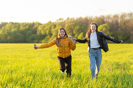 妈妈和女儿穿着便衣 在美丽的春天日落时在田里跑步幸福场地乐趣公园女性草地女士孩子微笑喜悦图片